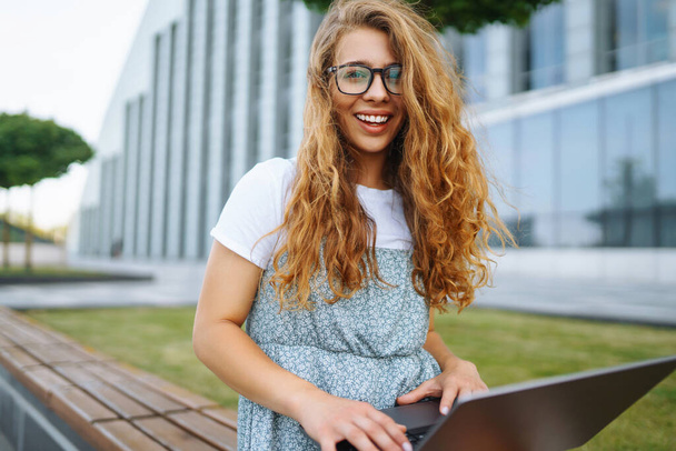Young woman sitting on the park  and using laptop and typing. Concept of education, online, freelance,  business. - Fotoğraf, Görsel