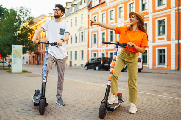 Young couple having fun driving electric scooter through the city. Active life. Ecological transportation concept. - Фото, зображення