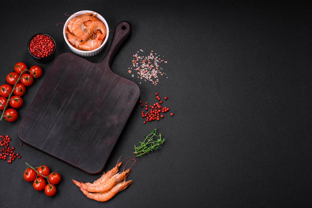 Ingredientes para cozinhar tomates cereja, camarão, sal e especiarias com um lugar para uma inscrição em um fundo de concreto escuro - Foto, Imagem