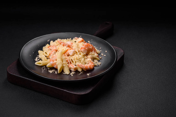 Delicious fresh penna pasta with shrimp, sauce, cheese, salt and spices on a dark concrete background - Фото, зображення