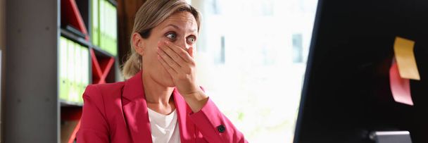 Geschäftsfrau blickt überrascht auf Monitor und bedeckt Mund mit der Hand. Schock der Emotionen und unerwartete Nachrichten online - Foto, Bild