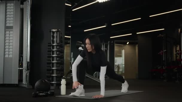 Kaukasische Sportlerin Fitnesstrainerin Trainerin athletische Frau führen Workout Stretchübung Yoga Praxis Körperdehnung aktiv fit Mädchentraining auf Fitnessmatte in Turnhalle gesunder Lebensstil - Filmmaterial, Video