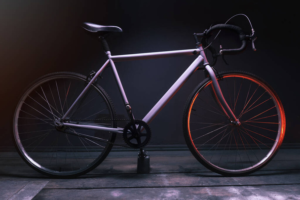 赤い光に照らされた暗い部屋でのグレーのストリートスポーツバイク - 写真・画像