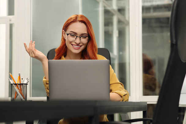 Happy woman having online meeting on laptop at desk in office - Фото, изображение