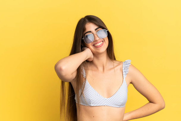 Mladá běloška žena v plavkách v letních prázdninách izolovaných na žlutém pozadí se směje - Fotografie, Obrázek