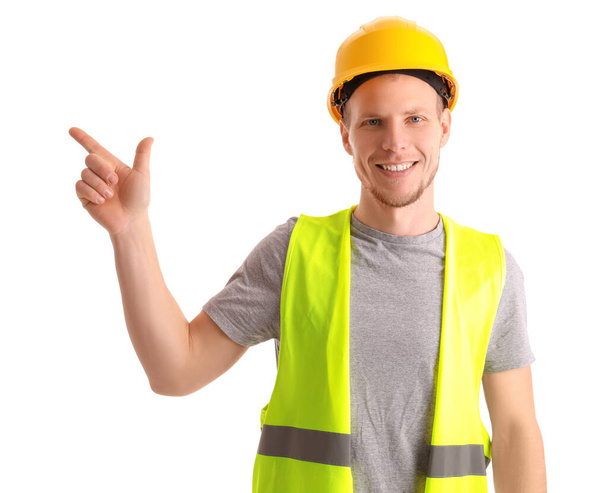 Male worker in vest and hardhat pointing at something on white background - Photo, Image