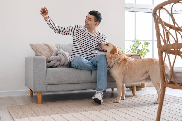 Labrador köpeği olan genç adam evde selfie çekiyor. - Fotoğraf, Görsel