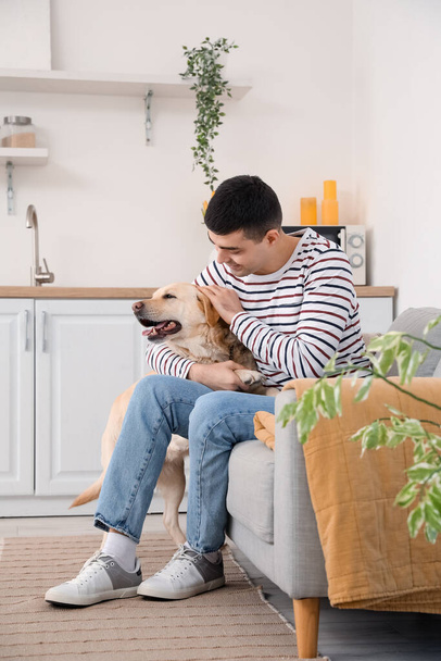 Young man with cute Labrador dog sitting in kitchen - Photo, Image