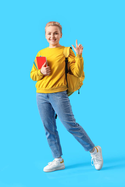 Female student with notebooks on blue background - Foto, Imagen