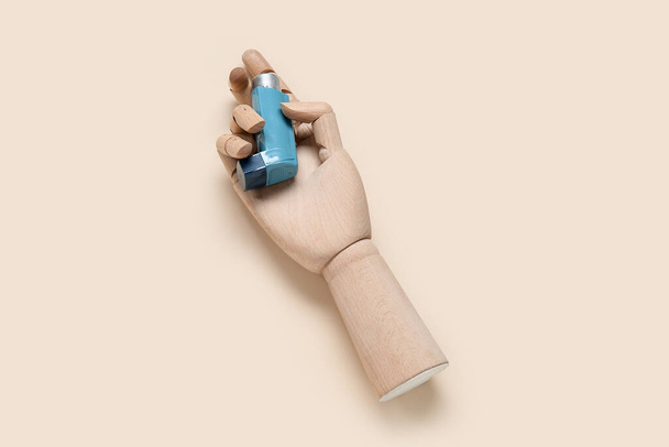 Mano in legno con inalatore d'asma su sfondo beige - Foto, immagini