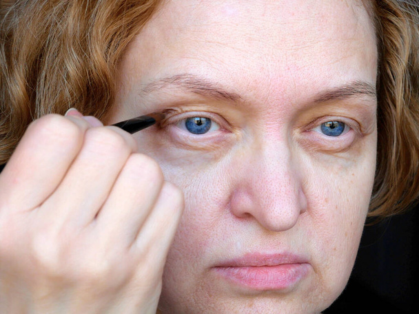 Keski-ikäisen naisen silmä roikkuvat silmäluomet tekevät meikkiä. Ptoosi on ylemmän silmäluomen roikkuminen, laiska silmä. Kosmetologia ja kasvojen käsite, ensimmäinen ryppyjä, lähikuva - Valokuva, kuva