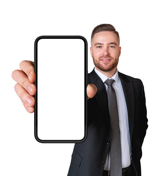 Portrait of cheerful young European businessman in elegant suit showing smartphone with blank mock up screen isolated on white background. Concept of communication and advertising - Valokuva, kuva
