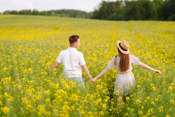 Young Couple in the blooming field. Nature, vacation, love, relax and lifestyle. Summer landscape.  - Foto, imagen