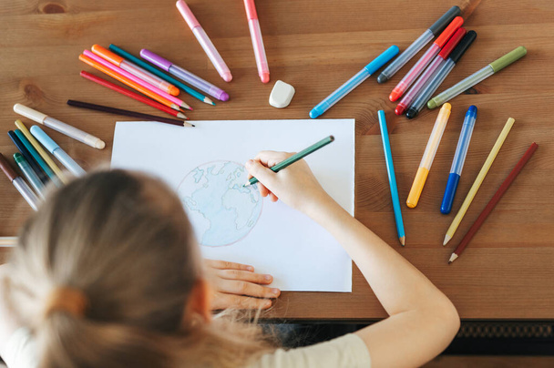 Dziecko dziewczyna rysunek z kolorowych ołówków w domu. Koncepcja ekologiczna, malowanie ziemi.  - Zdjęcie, obraz
