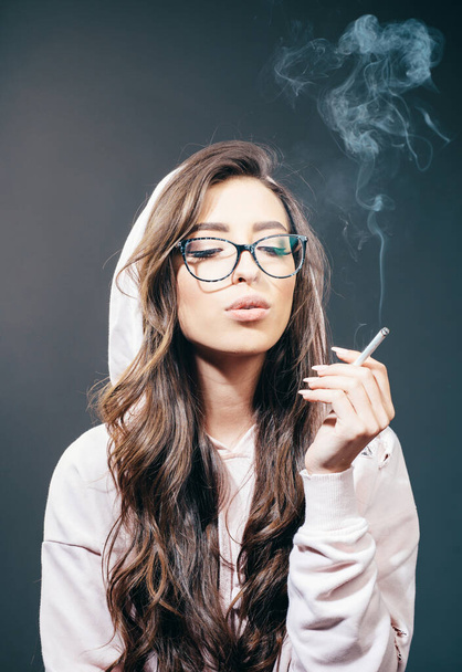 Рак лікує куріння. Гарненька жінка з довгим волоссям курить сигарету. Чуттєвий куріння наркоман або куріння. Жіночі звички куріння
. - Фото, зображення