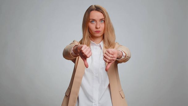 Dislike. Upset unhappy office woman in suit showing thumbs down sign gesture, expressing discontent, disapproval, dissatisfied, dislike. Business adult girl. Indoor studio shot on gray background - Photo, Image