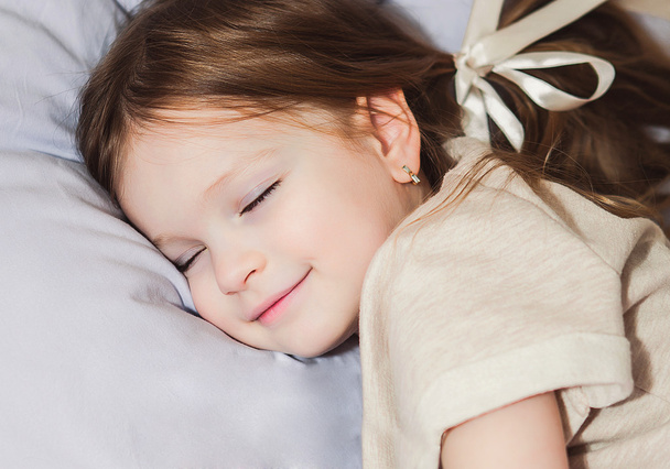 Маленька дівчинка в ліжку грає
 - Фото, зображення