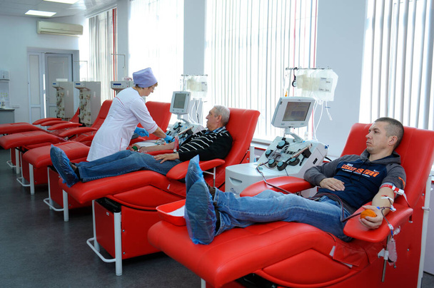 Νοσοκόμα που παίρνει αίμα από το μάταιο του δότη, υποδερμική βελόνα, σωλήνες, δοχείο με αίμα. Δημοτικός σταθμός μετάγγισης αίματος. 5 Απριλίου 2022. Κίεβο, Ουκρανία - Φωτογραφία, εικόνα