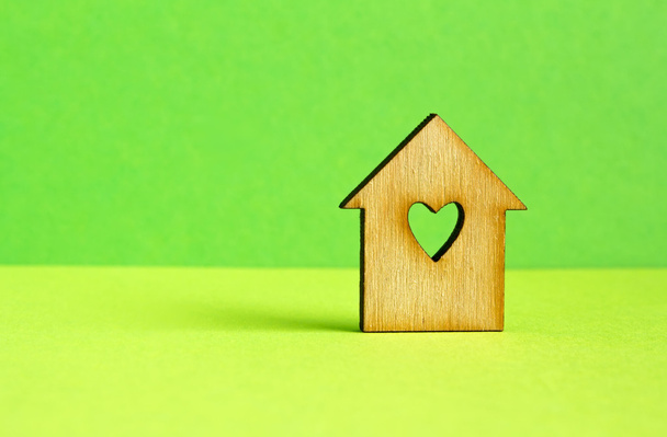 Houten huis met gat in de vorm van hart op groene achtergrond - Foto, afbeelding