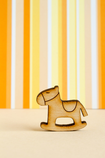 Деревянная икона детского скачущего коня на оранжевом полосатом бэкгре
 - Фото, изображение