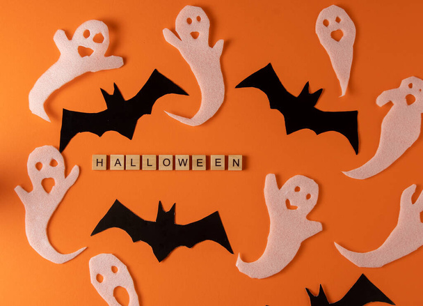 White ghosts and bat craft for Halloween party. Wrapping paper ghost on orange background top view. Cartoon creepy Whisper. DIY hand made. Set boo characters. Word wooden letter phrase. - Foto, imagen