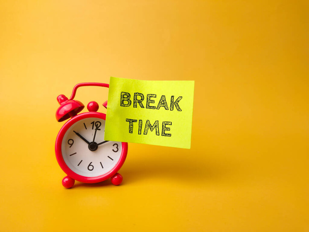 Reloj despertador y nota adhesiva con la palabra BREAK TIME sobre fondo amarillo - Foto, imagen