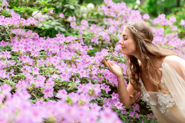 A beautiful pregnant woman near a blooming rhododendron bush - Photo, image