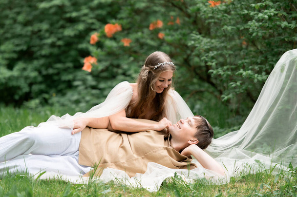 Hapy έγκυος ζευγάρι αγκαλιάζει στον ανθισμένο κήπο. Μελλοντικοί γονείς στο ανθισμένο πάρκο ροδόδεντρο. - Φωτογραφία, εικόνα