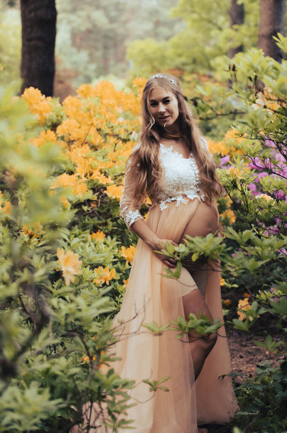  Zwangere vrouw in het rododendron park. Close-up van zwangere buik in bloeiende natuur.  - Foto, afbeelding