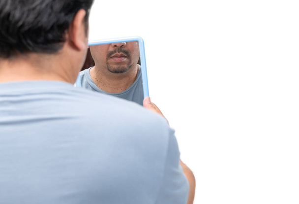 Homem barbudo olhando no espelho para marcas de pele ou acrocordão em seu pescoço isolado em fundo branco. Conceito de saúde - Foto, Imagem