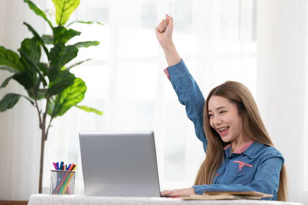 Entrepreneur of beautiful business asian young woman working online with laptop and celebrating at home with her work success cheerful and happiness. Small Business Startup concept - 写真・画像