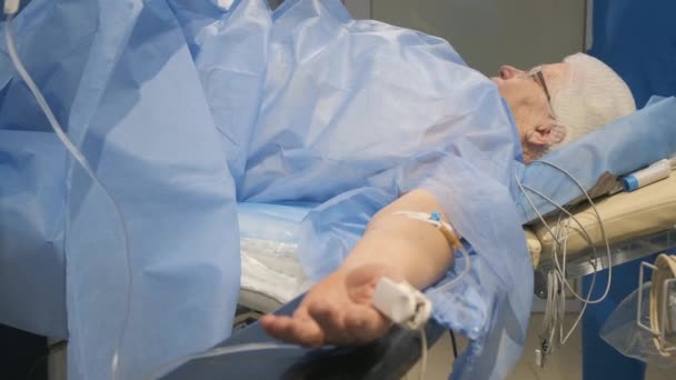 An old woman is on the operating table in the surgery department, talking to the doctor during anesthesia. Modern European clinic - Footage, Video