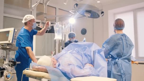 Chirurdzy operują nogi starszej kobiety z żylakami. - Proces pracy chirurgów. Pionowe wideo - Materiał filmowy, wideo