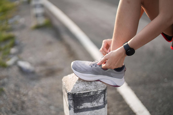 Running shoes. close up female athlete tying laces for jogging on road. Runner ties getting ready for training. Sport lifestyle. copy space. - Photo, Image