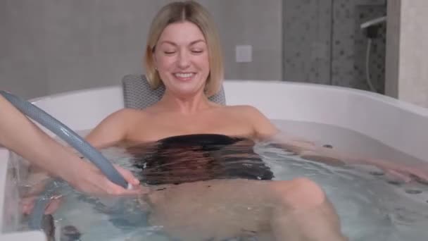 Profesjonalny lekarz daje kobiecie hydromasaż. Zabieg hydromasażu w specjalnej kąpieli z lekami. Nowoczesny salon spa. Pionowe wideo - Materiał filmowy, wideo