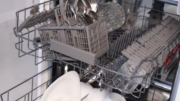 Close-up of a womans hand putting kitchen utensils into a modern dishwasher. The concept of cleanliness in the house - Footage, Video