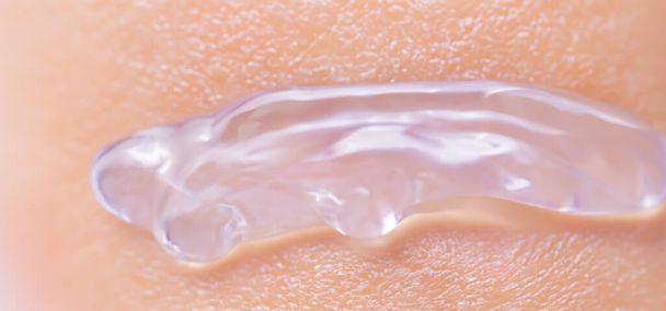 Κολλαγόνο και υαλουρονικό γέλη ορού στο δέρμα. Πιτσιλιές από υαλουρονικό τζελ. Υγρό τζελ υαλουρονικού οξέος στο δέρμα. Καλλυντική υφή τζελ νερού σε ανθρώπινο δέρμα. Υφή φόντο. προϊόν φροντίδας δέρματος. - Φωτογραφία, εικόνα