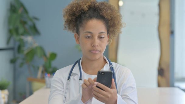 Female African Doctor Using Smartphone in Clinic - Zdjęcie, obraz