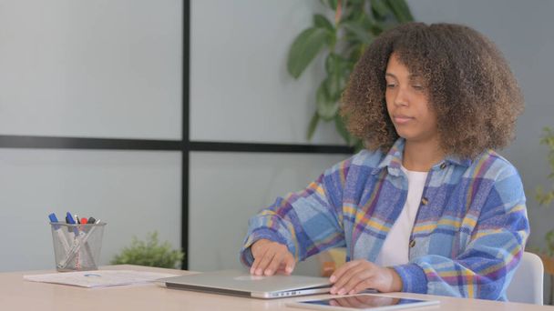 Mujer afroamericana que viene a la oficina y comienza a trabajar en el ordenador portátil - Foto, Imagen