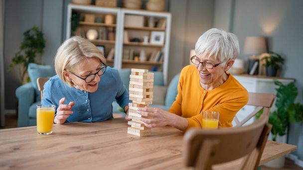 kaksi vanhempaa naista nainen ystäviä tai perhe sisaret pelata vapaa lautapeli kotona hauskaa eläkeläinen isoäiti viettää aikaa yhdessä kypsän tyttärensä kanssa - Valokuva, kuva
