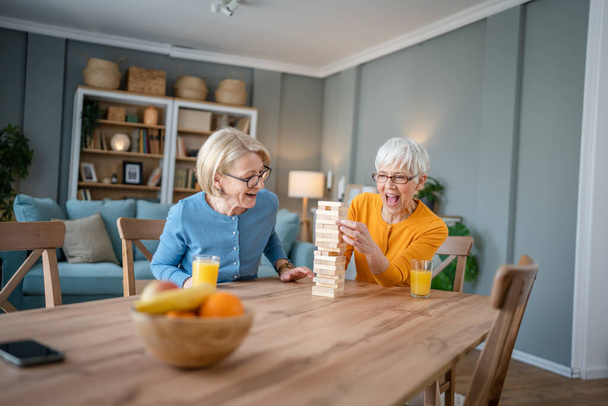 kaksi vanhempaa naista nainen ystäviä tai perhe sisaret pelata vapaa lautapeli kotona hauskaa eläkeläinen isoäiti viettää aikaa yhdessä kypsän tyttärensä kanssa - Valokuva, kuva