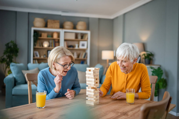 two senior women female woman friends or family sisters play leisure board game at home have fun pensioner grandmother spend time together with their mature daughter - Foto, afbeelding