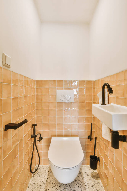 a toilet in a bathroom with tiled walls and white fixtures on the wall behind it is a sink, fae - Foto, Imagen
