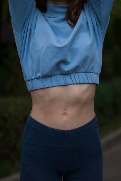 Widok na atletyczne ciało dziewczyny w niebieskim stroju gimnastycznym w pochmurnym tkaniu - Zdjęcie, obraz