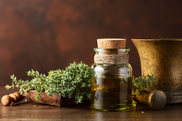 Botella de aceite esencial de tomillo con tomillo fresco sobre una vieja mesa de madera. Copiar espacio. - Foto, Imagen