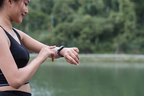 image d'une belle femme asiatique sportive en vêtements de sport vérifiant ses calories brûlées et courant des kilomètres sur sa smartwatch après une course en plein air. - Photo, image