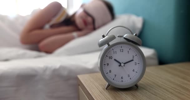 Frau oder Teenager schläft im Bett mit Augenmaske und 10-Uhr-Wecker. Morgenschlaf und Aufwachen - Filmmaterial, Video