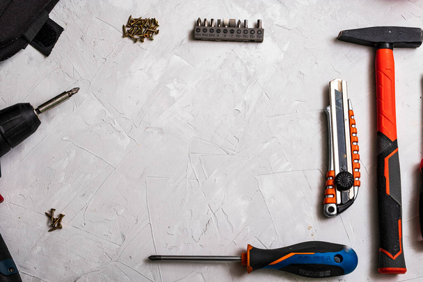 Top view of working tools, hammer, screwdriver, pliers, electric drill, tape measure, screws on a white background. - Foto, Imagem