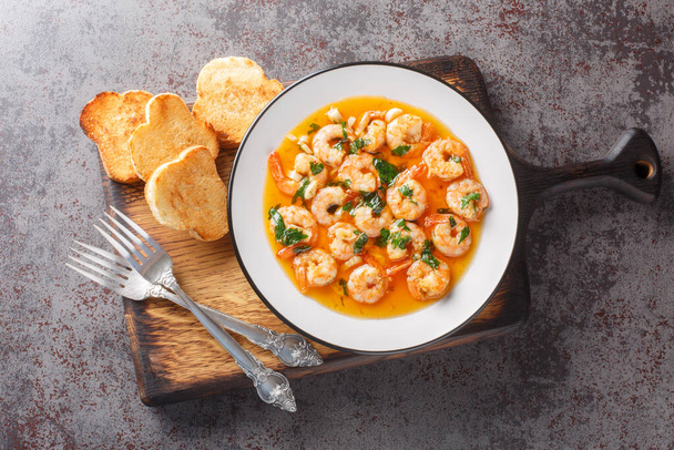 Spanish Garlic Shrimp with an ajillo sauce closeup on the plate on the wooden board. Horizontal top view from abov - Φωτογραφία, εικόνα