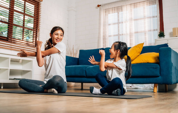 Молода мама і дочка займаються фізичними вправами у вітальні вдома, здорові і пристосовані сім'ї роблять домашні вправи на йогу, сім'я грає разом вдома, сім'я зі здоровим способом життя
 - Фото, зображення